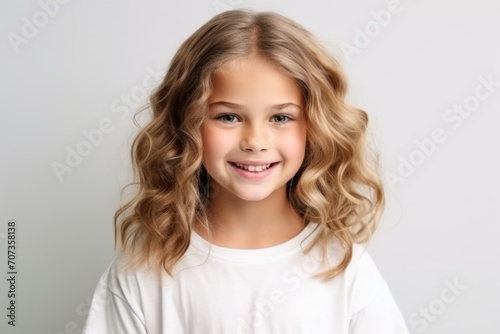 Portrait of a cute little girl with blond curly hair over grey background
