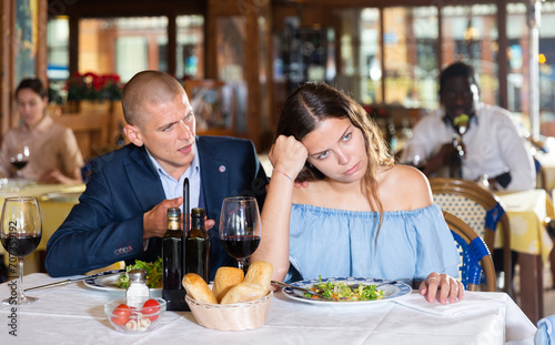 Disgruntled man and woman quarreling and emotionally gesturing  having bad date in restaurant