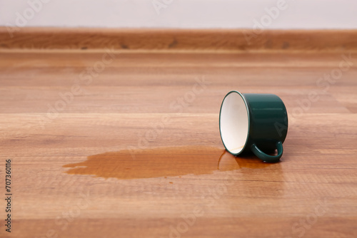 Wooden laminate floor with overturned cup of tea