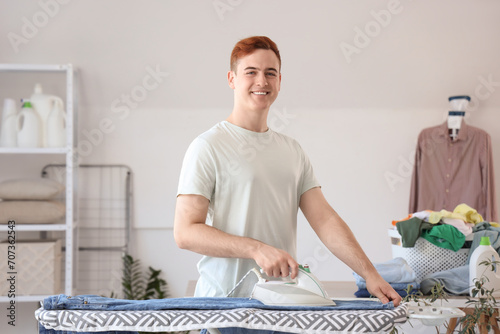 Handsome young man ironing ...