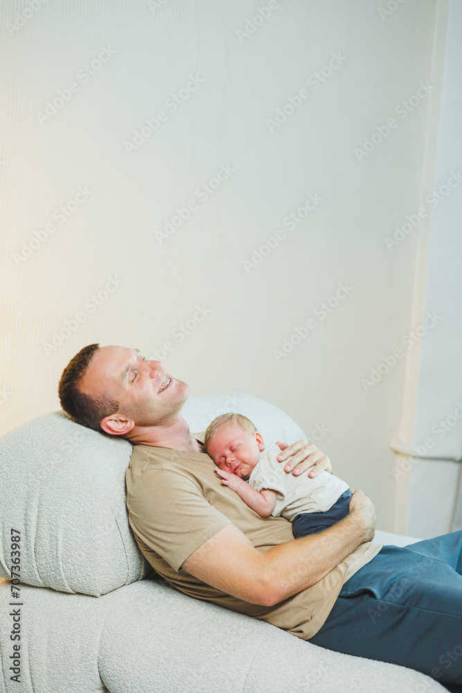 A happy young father holds his newborn son in his arms. Parenthood concept. Father and little son A happy young father holds his newborn son in his arms. Parenthood concept. Father and little son