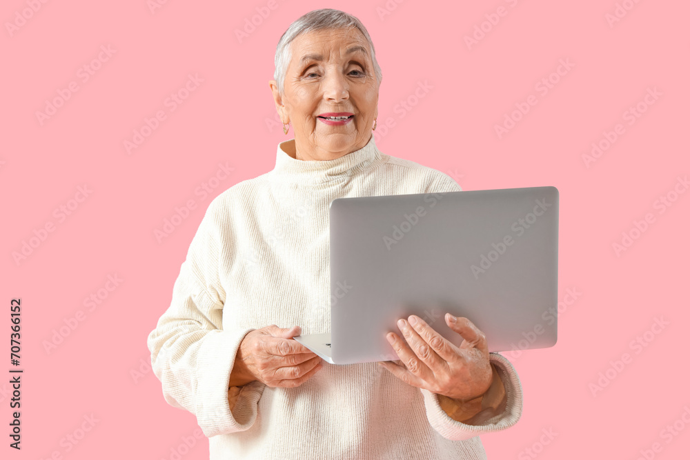 Senior woman with laptop on pink background Senior woman with laptop on pink background