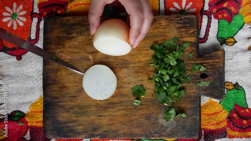 Manos cortando cebolla en tabla de madera para aros de cebolla con perejil. photo