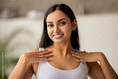 Attractive millennial indian woman touching her silky skin