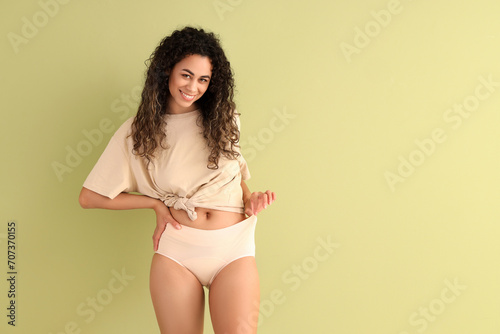 Young African-American woman in menstrual panties on green background