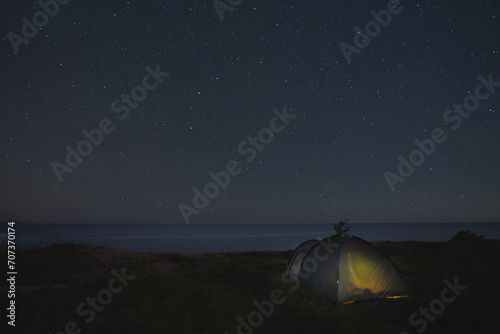 Night scene, camping with a tent on the steep seashore in Paldiski under the starry sky.
