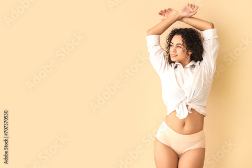 Young African-American woman in menstrual panties on beige background photo