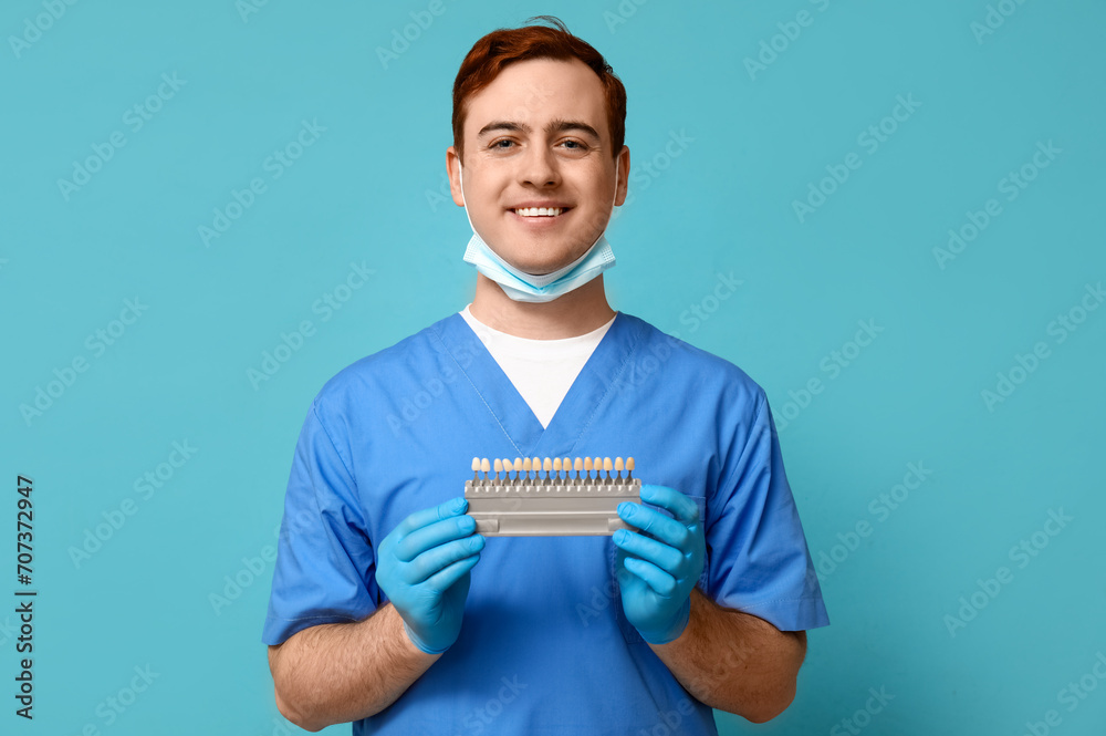 Male dentist with dental shade guide on blue background. World Dentist Day Male dentist with dental shade guide on blue background. World Dentist Day