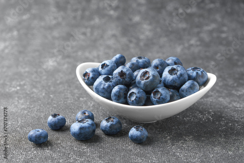 Fresh blueberries in a small round bowl on dark concrete background. Organic berries, healthy food, wild berries.
