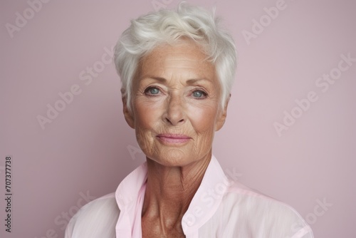 Portrait of a senior woman looking at the camera over pink background