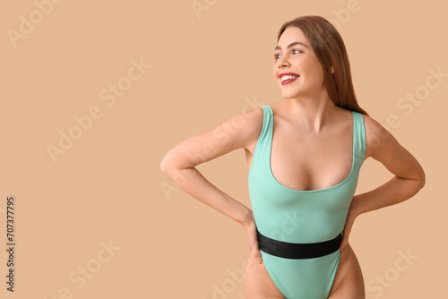 Beautiful young woman in tank swimsuit on beige background © Pixel-Shot