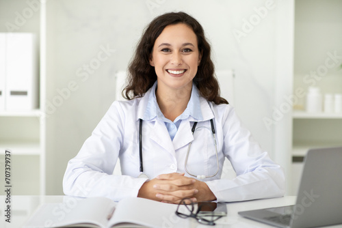Portrait of beautiful millennial woman doctor sitting at her office