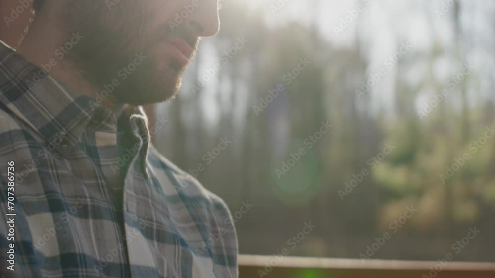 Young man sitting on front porch reading his Bible and drinking coffee