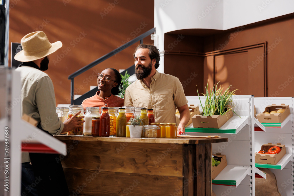 Φωτογραφία Caucasian boyfriend and African American girlfriend interact enthusiastically with storekeeper in eco friendly shop