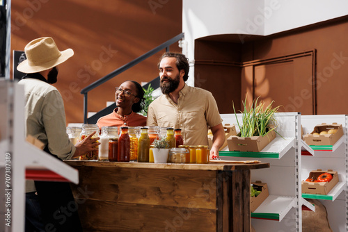 Фотография Caucasian boyfriend and African American girlfriend interact enthusiastically with storekeeper in eco friendly shop