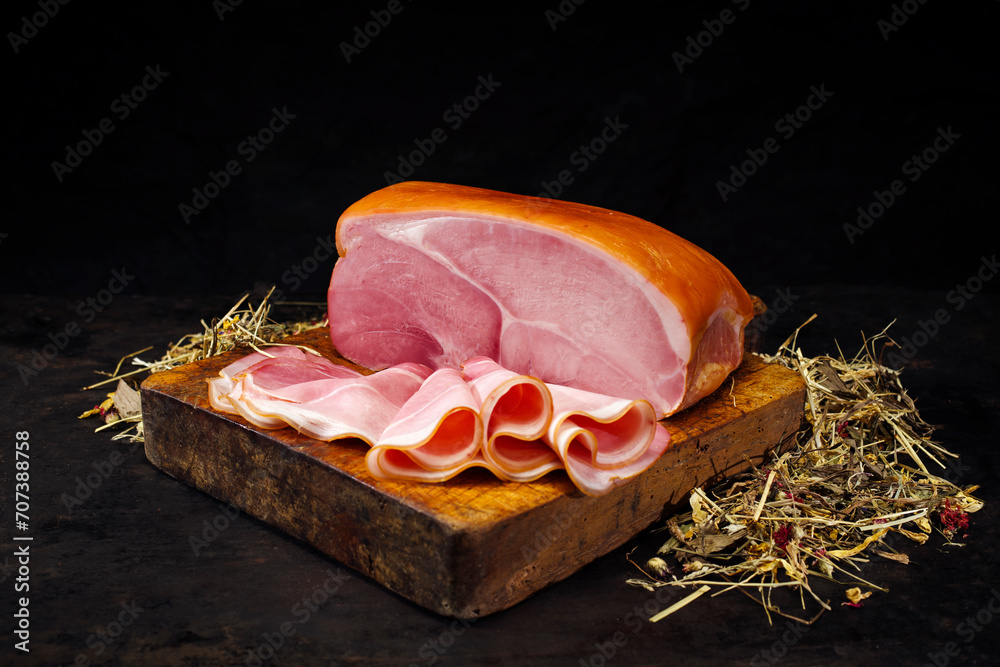 Φωτογραφία Traditioneller Südtiroler Bauernschinken aufgeschnitten und am Stück mit Kräuter
