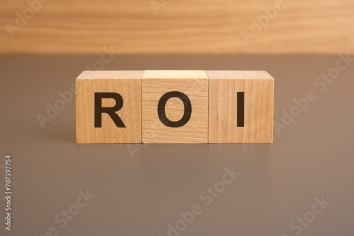 the text ROI is written on three cubes standing on a brown surface. business concept.