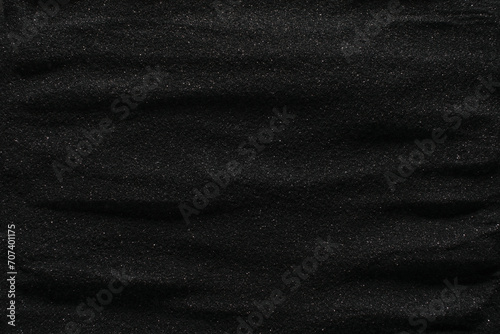 Dunes of dark black sand. Stripes and ripples of smooth volcanic sand texture or wallpaper. Wave pattern in black sand background.