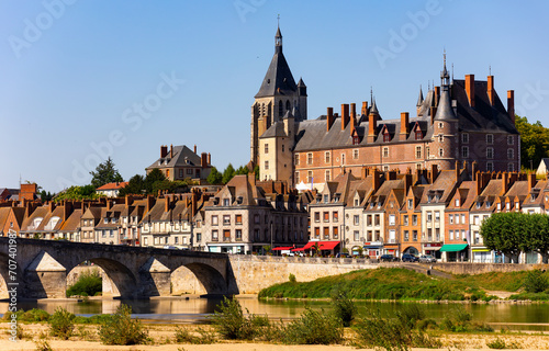 Scenic summer view of Gien townscape overlooking arched bridge across Loire river and medieval Chateau de Gien dominating over residential houses on sunny day  France
