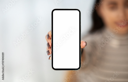 Millennial arab lady show smartphone with empty screen, for chatting