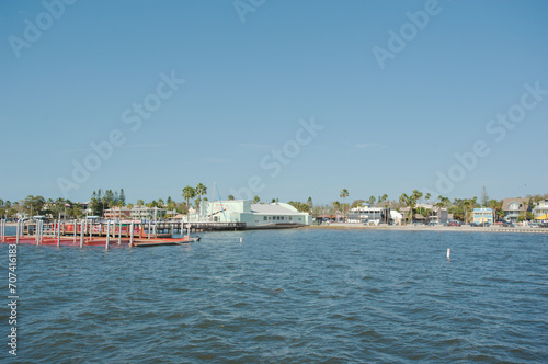 View from pier in Gulfport, Florida looking back across towards boat dock and beach. With blue water and clear blue sky on a sunny day.