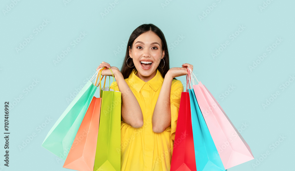 Emotional brunette woman showing colorful shopping bags