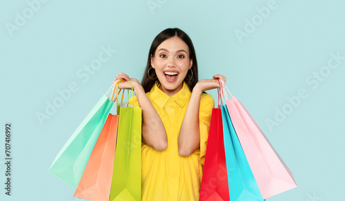 Emotional brunette woman showing colorful shopping bags © Prostock-studio