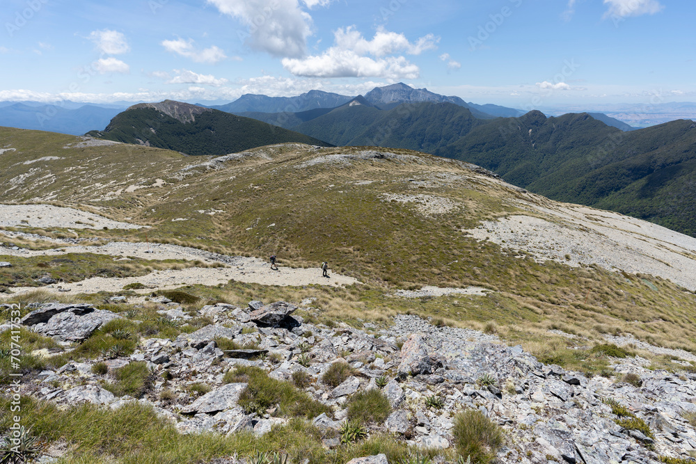 Hiking in the mountains of New Zealand featuring scenic landscape, blue sky and clouds