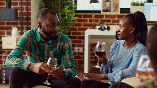 African american man at apartment party talking with woman sharing interesting story, flirting with her. Guest at home gathering interested in charming BIPOC host, chatting with her photo