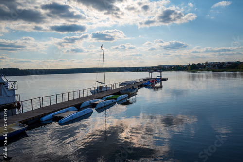 pier with boats on the lake on the background of a sunset sky with clouds