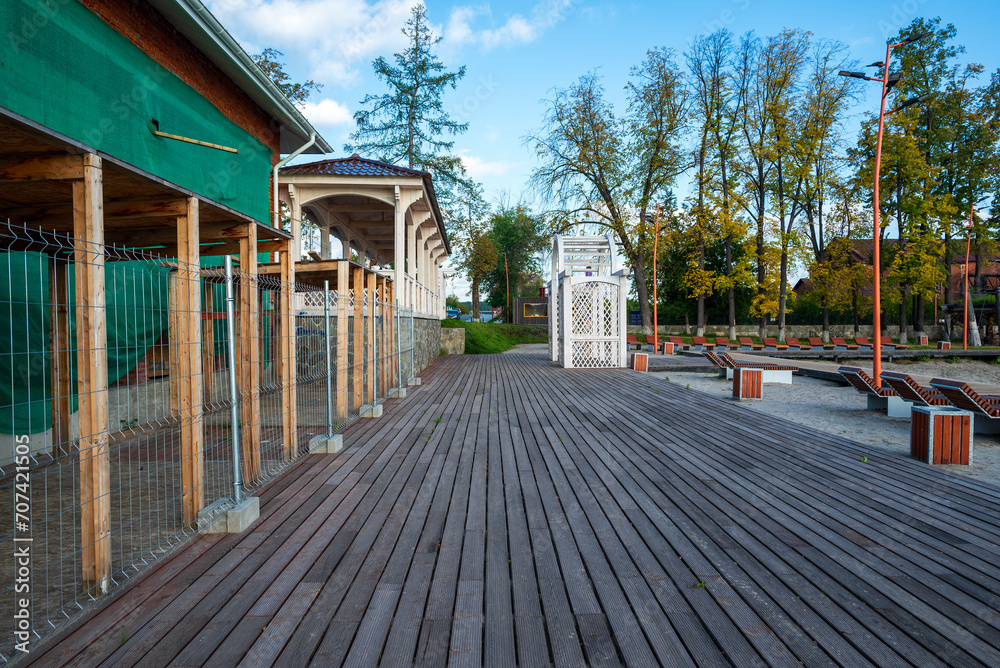 wooden embankment with pier on the background of the park