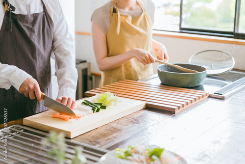 キッチンで料理をする夫婦・包丁で野菜を切る男性
 photo