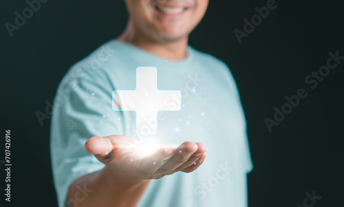 Mental health care mental rejuvenation concept. Man smiling good mood hand holding virtual blue plus sign for positive thinking mindset or healthcare insurance symbol.