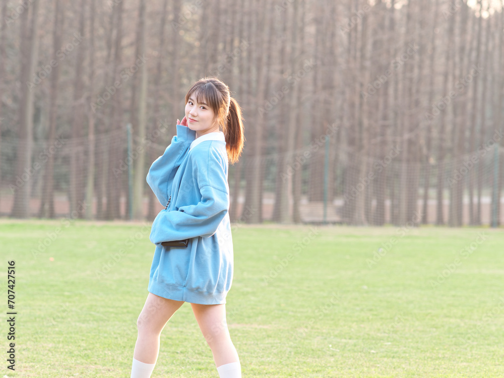 Beautiful young Chinese woman posing on green grass field in sunny summer day, wearing blue loose oversized top, mini skirt and white shoes. Emotions, people, beauty, youth and lifestyle portrait. Beautiful young Chinese woman posing on green grass field in sunny summer day, wearing blue loose oversized top, mini skirt and white shoes. Emotions, people, beauty, youth and lifestyle portrait.