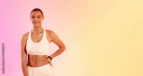 Photos Smiling young fitness enthusiast in a white sports bra and light shorts stands c