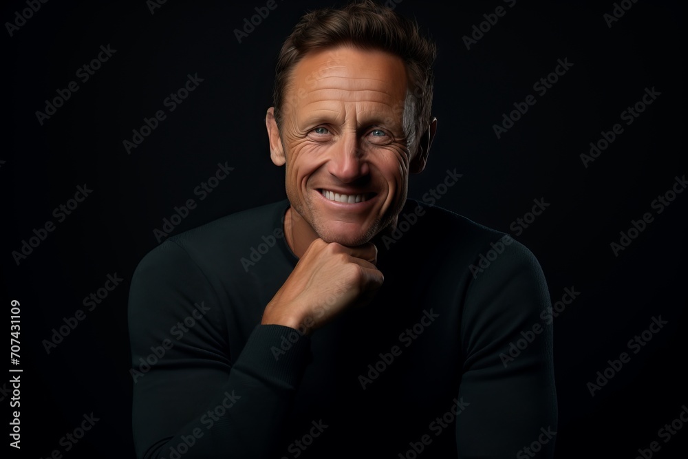Portrait of a handsome mature man in a black sweater on a black background.