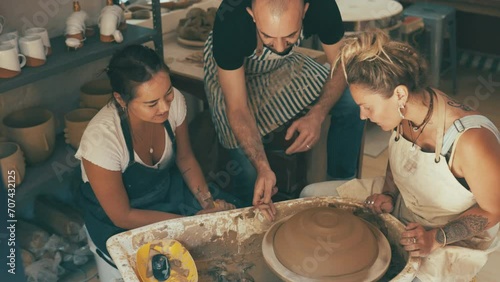 Pottery wheel, teacher and class of people learning workshop skill, sculpture design or craftsmanship. Ceramic studio, mentor and students teamwork on handmade product, creative project or mud art photo