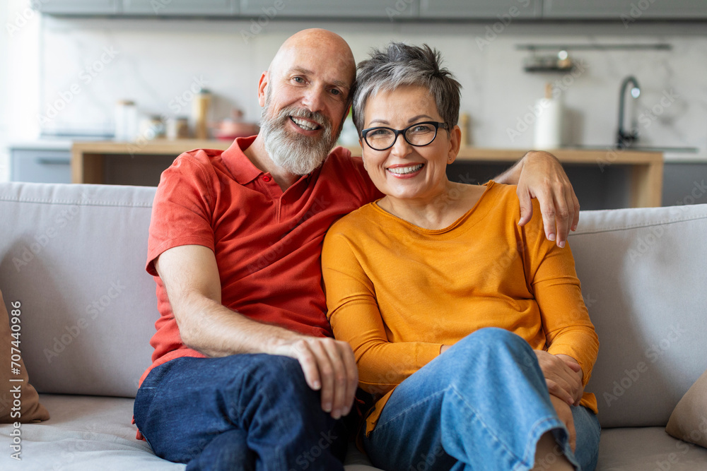 Affectionate senior couple sitting on comfortable sofa and embracing Affectionate senior couple sitting on comfortable sofa and embracing
