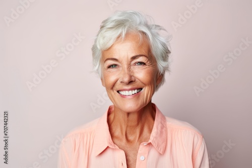 Smiling senior woman. Portrait of a smiling senior woman looking at camera while standing against pink background
