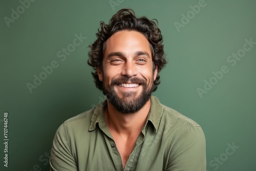 Portrait of a handsome man smiling at the camera while standing against green background