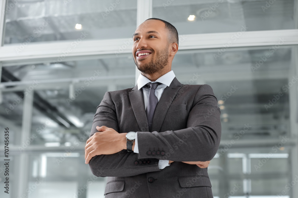 Happy man with crossed arms in office, low angle view. Lawyer, businessman, accountant or manager Happy man with crossed arms in office, low angle view. Lawyer, businessman, accountant or manager