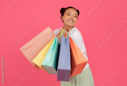 Cheerful Young Asian Shopaholic Woman Holding Bright Paper Shopping Bags