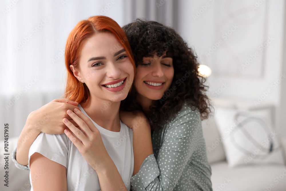 Portrait of happy young friends hugging at home