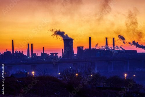 steel factory at sunset causing pollution smoke, global warming issue causing environmental issues ,view over the bridge