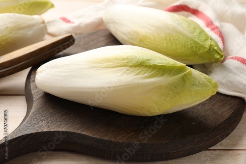 Raw ripe chicories on wooden table, closeup photo