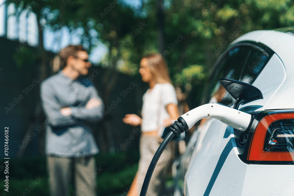 Φωτογραφία Young couple travel with EV electric car charging in green sustainable city outd