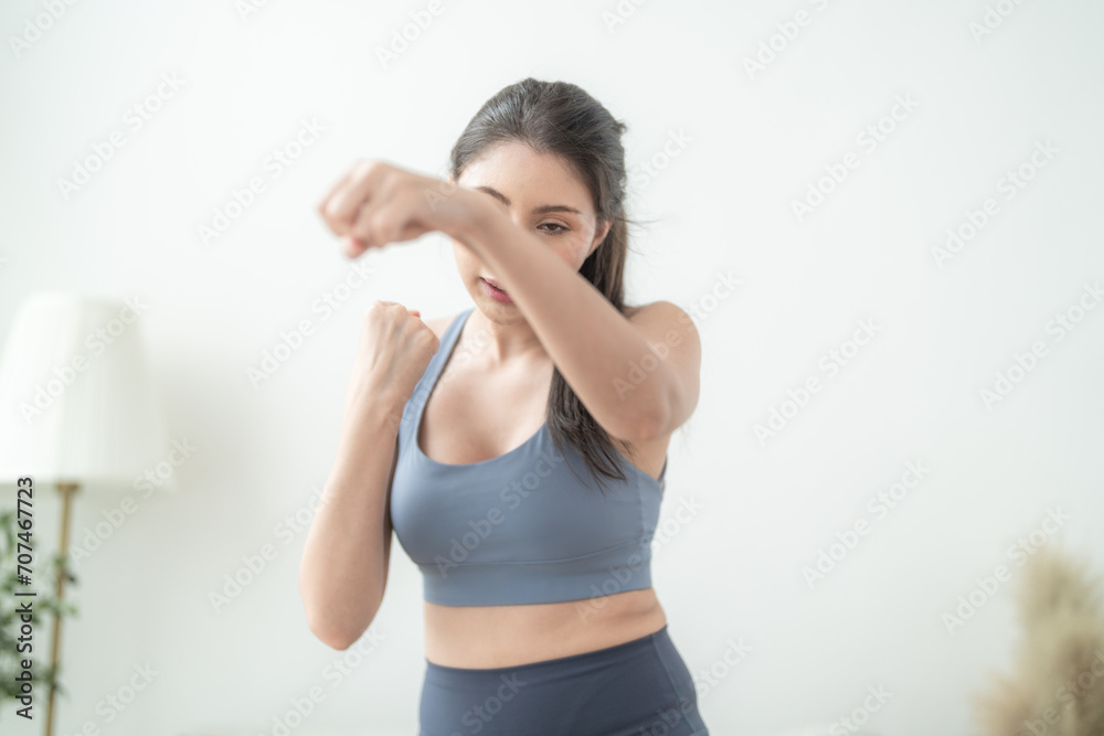 Attractive and strong woman stretching before fitness at indoor house. Healthy lifestyle. woman warm up by boxing in the air. Young female with slim body punching boxing footwork cardio exercise.