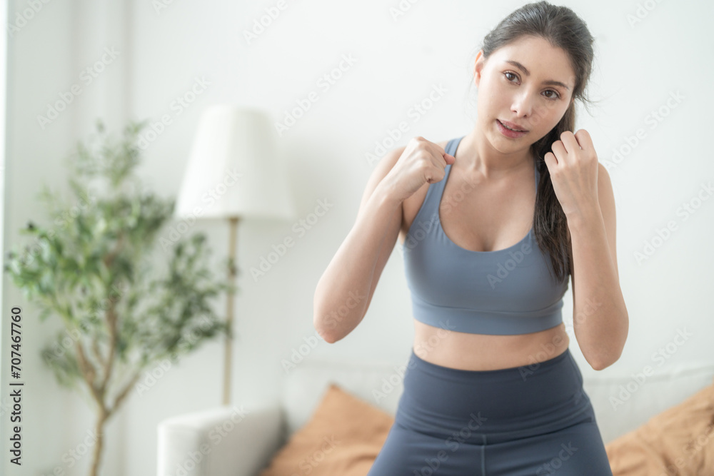 Attractive and strong woman stretching before fitness at indoor house. Healthy lifestyle. woman warm up by boxing in the air. Young female with slim body punching boxing footwork cardio exercise.