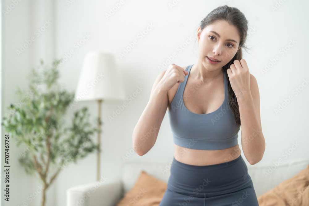 Attractive and strong woman stretching before fitness at indoor house. Healthy lifestyle. woman warm up by boxing in the air. Young female with slim body punching boxing footwork cardio exercise.