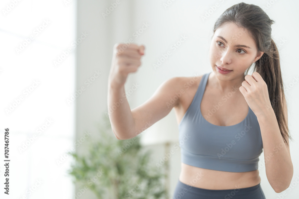 Attractive and strong woman stretching before fitness at indoor house. Healthy lifestyle. woman warm up by boxing in the air. Young female with slim body punching boxing footwork cardio exercise. Attractive and strong woman stretching before fitness at indoor house. Healthy lifestyle. woman warm up by boxing in the air. Young female with slim body punching boxing footwork cardio exercise.